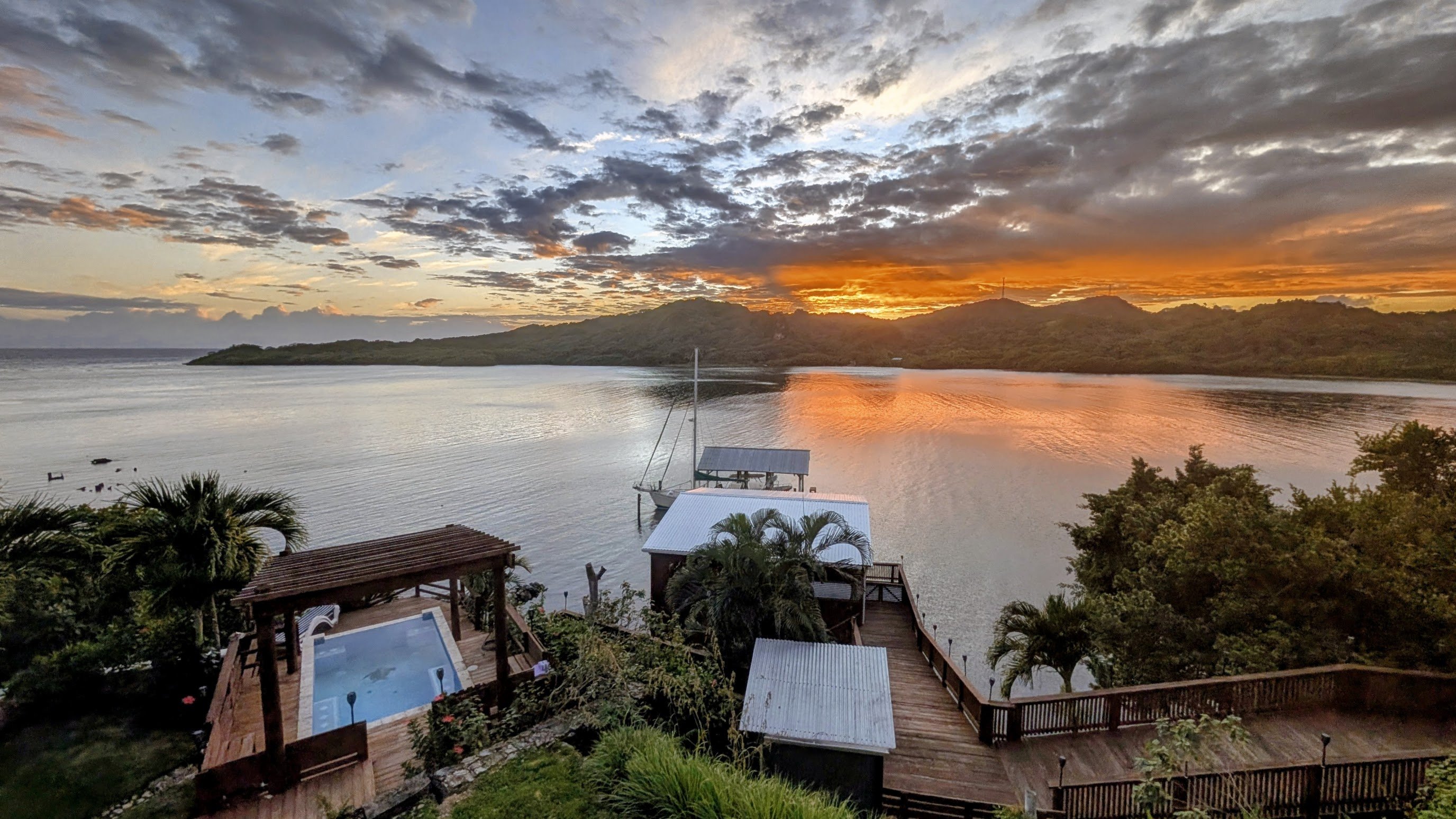 View from Resort Takeover — pool, dock, and Carib Bight at sunset